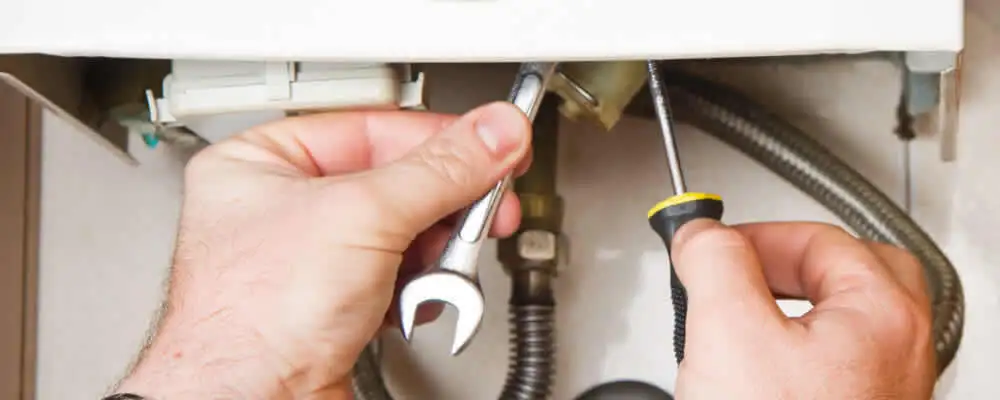 Boiler repair technician tightening pipe fittings and connections in Newton, MA