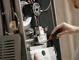 Furnace repair technician inspecting internal components and wiring in Newton, MA