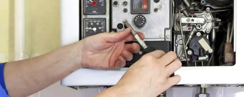 Heating repair technician adjusting boiler controls and components in Newton, MA