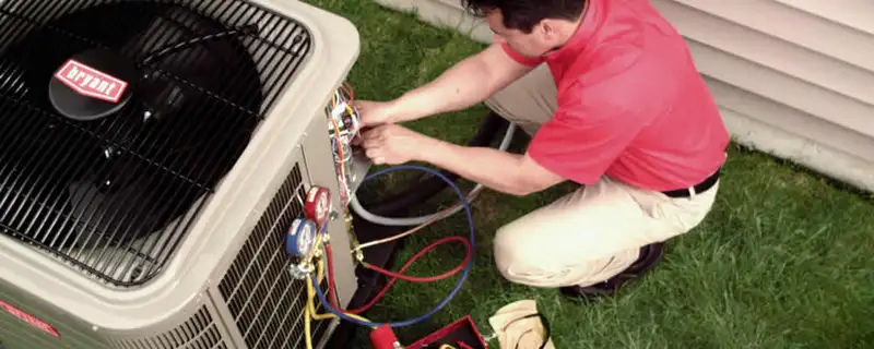 HVAC technician servicing an outdoor air conditioner unit in Newton, MA
