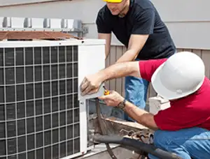 HVAC technicians repairing an outdoor AC unit on a rooftop in Newton, MA