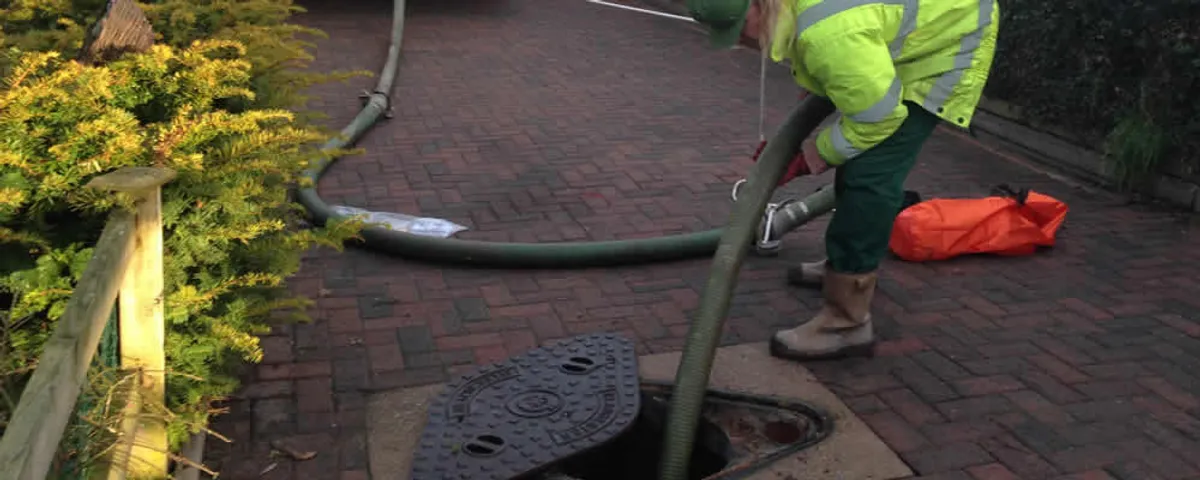 Septic tank cleaning technician servicing a septic tank with a vacuum hose in Newton, MA